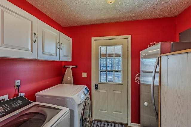 laundry area featuring cabinet space, a textured ceiling, and separate washer and dryer