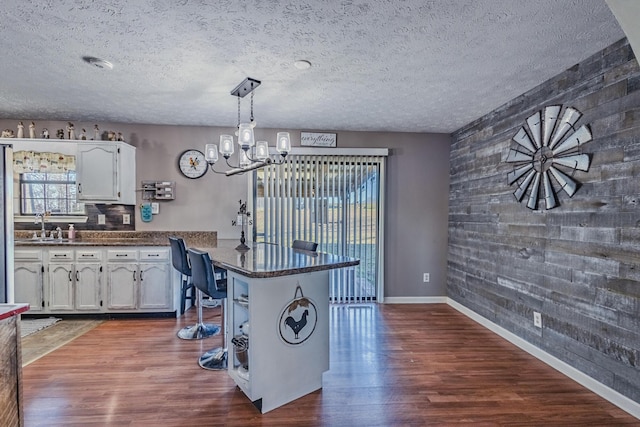 kitchen with dark wood finished floors, a peninsula, white cabinets, and a textured ceiling