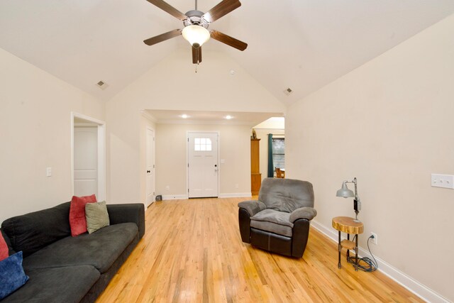 living room with ceiling fan, vaulted ceiling, and light wood-type flooring