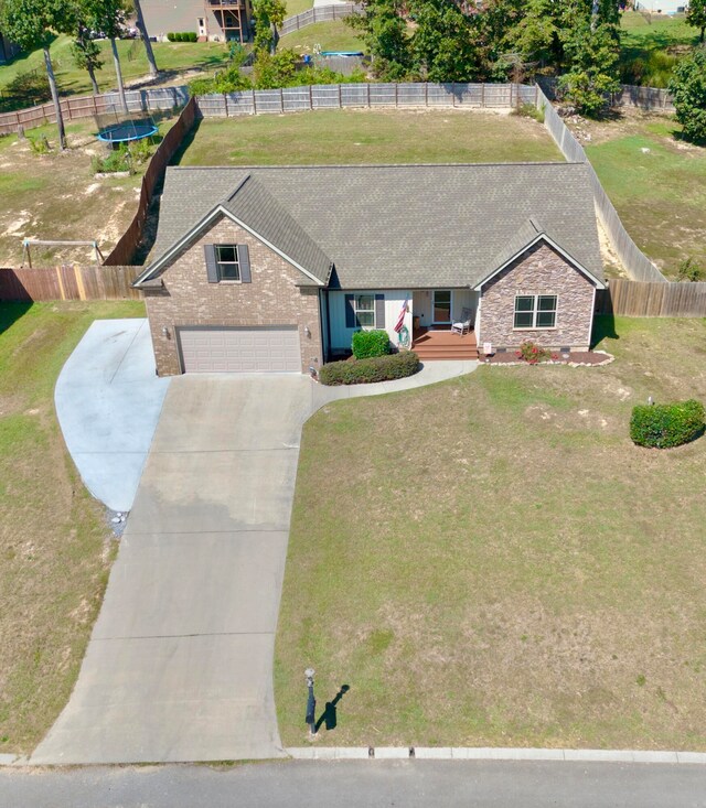 ranch-style house with a front yard, a trampoline, and a garage