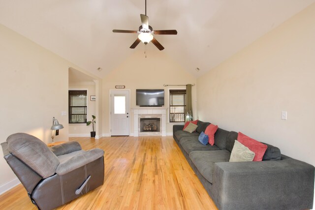 living room featuring a tile fireplace, ceiling fan, high vaulted ceiling, and hardwood / wood-style flooring