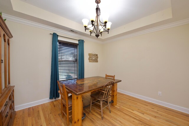 dining space featuring a chandelier, light hardwood / wood-style floors, ornamental molding, and a tray ceiling