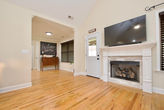 unfurnished living room with a fireplace, vaulted ceiling, and light wood-type flooring