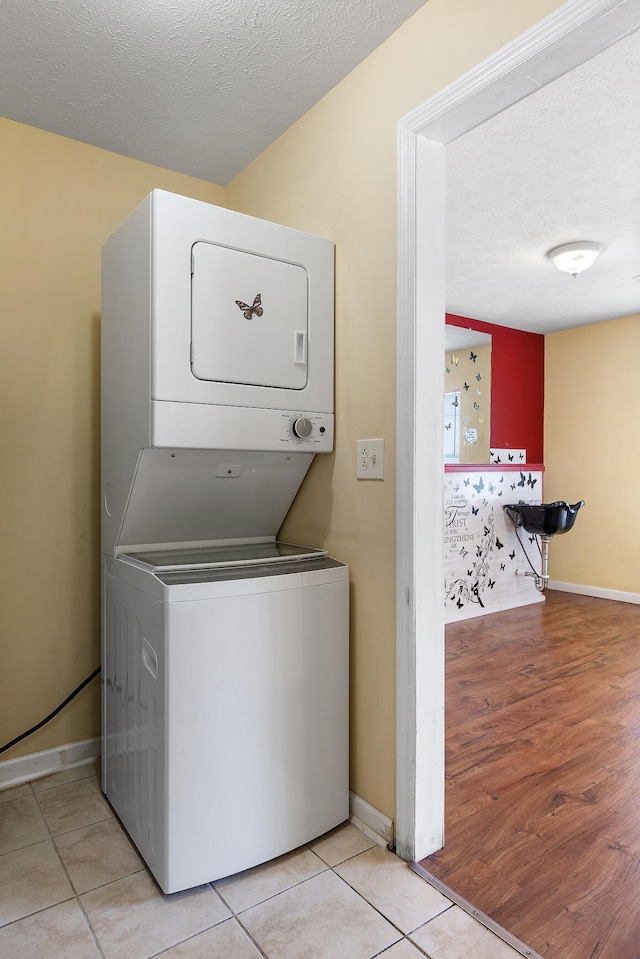 washroom featuring stacked washer / drying machine, light wood-type flooring, and a textured ceiling