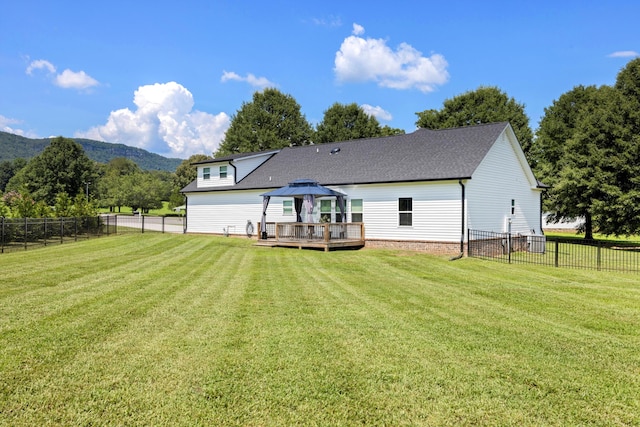 rear view of property featuring a deck with mountain view, a gazebo, and a lawn