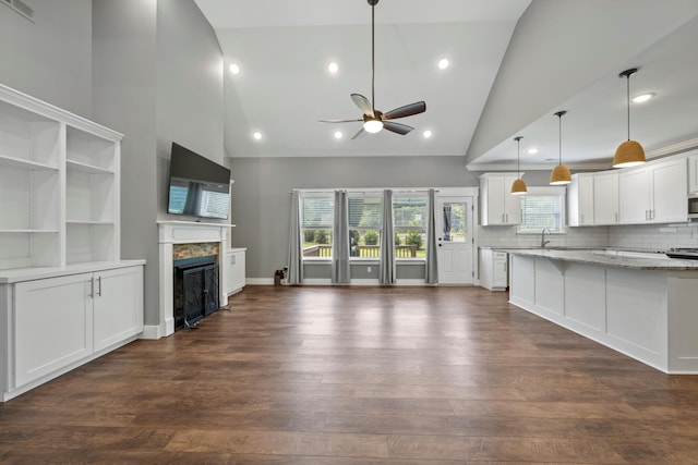 unfurnished living room featuring high vaulted ceiling, ceiling fan, dark wood-type flooring, and sink