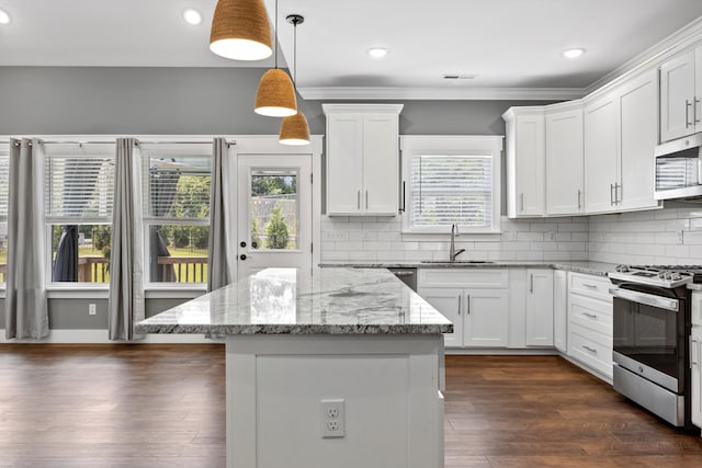 kitchen with appliances with stainless steel finishes, light stone counters, sink, decorative light fixtures, and white cabinets