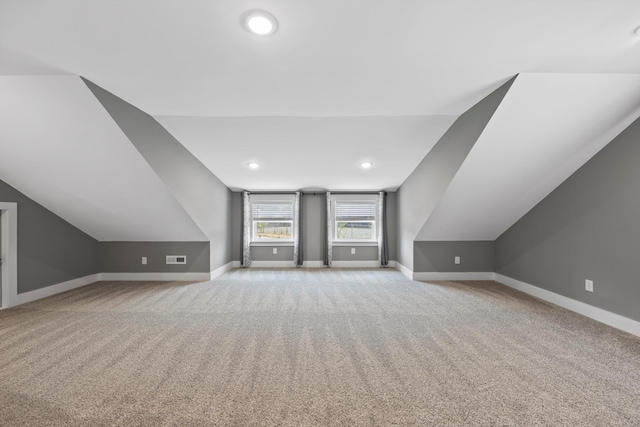 additional living space featuring light colored carpet and vaulted ceiling