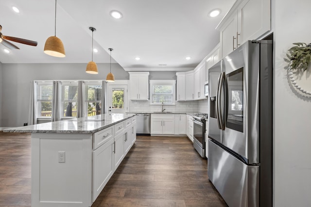 kitchen featuring dark hardwood / wood-style flooring, stainless steel appliances, a center island, white cabinetry, and hanging light fixtures