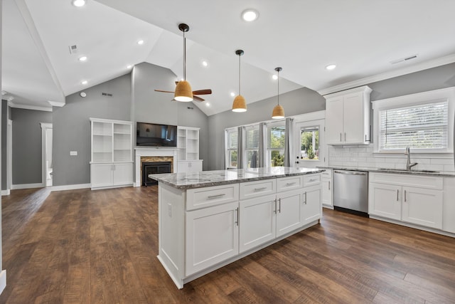 kitchen featuring white cabinets, stainless steel dishwasher, ceiling fan, a kitchen island, and light stone counters