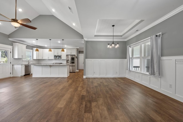 unfurnished living room with sink, dark wood-type flooring, vaulted ceiling, ceiling fan with notable chandelier, and ornamental molding