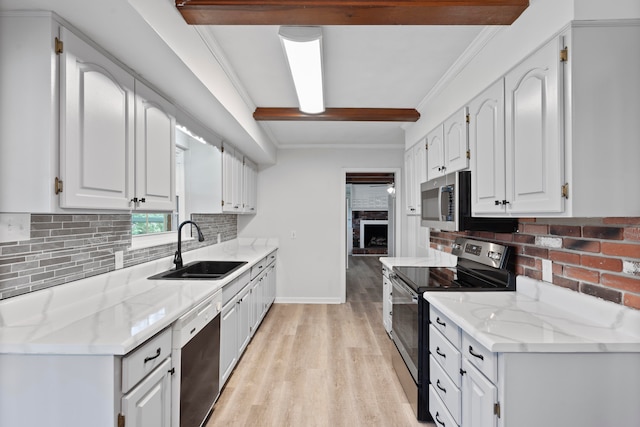 kitchen with white cabinets, appliances with stainless steel finishes, light stone counters, and sink