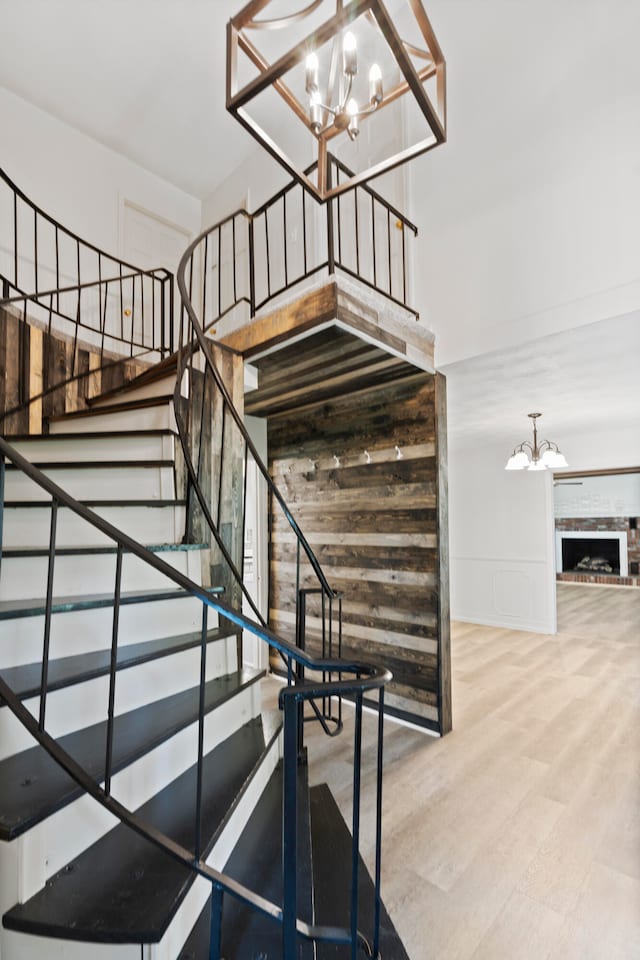 staircase featuring a fireplace, hardwood / wood-style floors, and an inviting chandelier