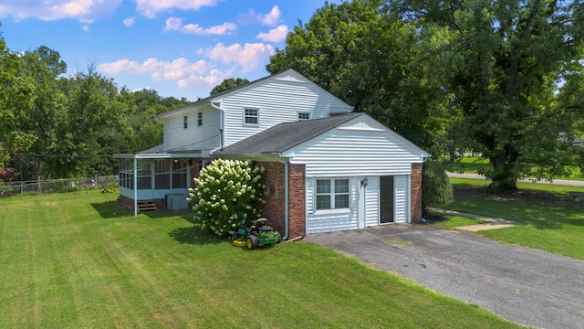 rear view of house with a lawn and a sunroom