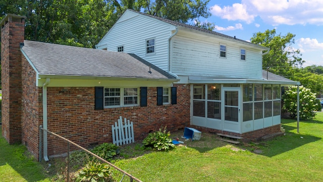 rear view of property with a yard and a sunroom