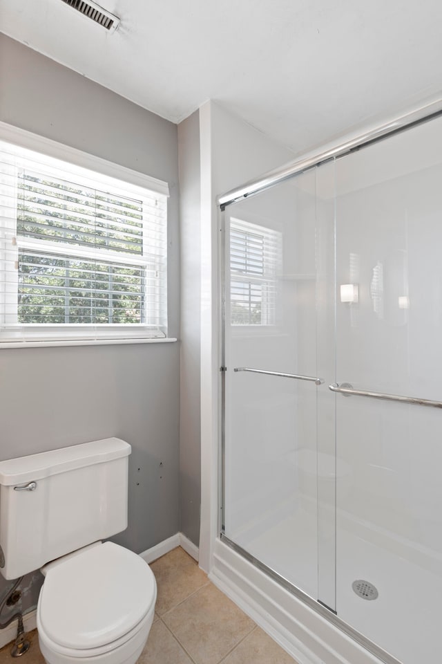 bathroom featuring tile patterned flooring, toilet, and walk in shower