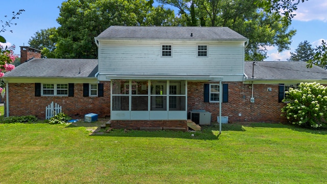 back of house featuring a lawn, a sunroom, and central AC unit