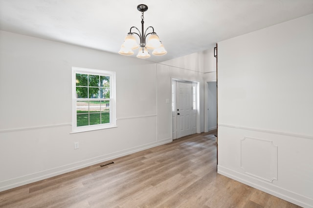 unfurnished room with light wood-type flooring and a chandelier