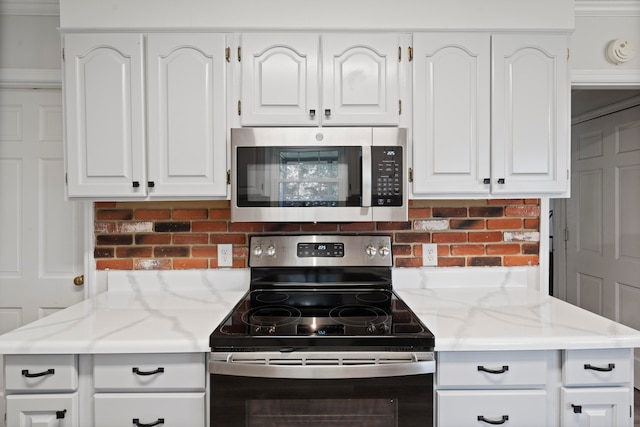 kitchen with light stone countertops, stainless steel appliances, white cabinetry, and tasteful backsplash