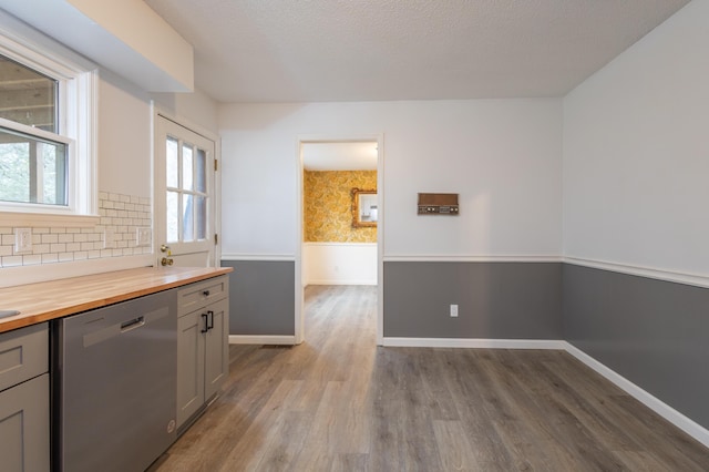 kitchen with butcher block counters, stainless steel dishwasher, dark hardwood / wood-style floors, gray cabinets, and decorative backsplash