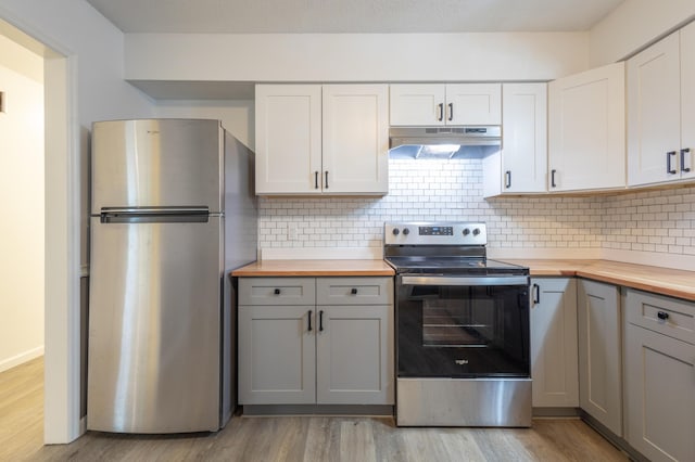 kitchen featuring white cabinets, gray cabinets, light wood-type flooring, appliances with stainless steel finishes, and butcher block counters