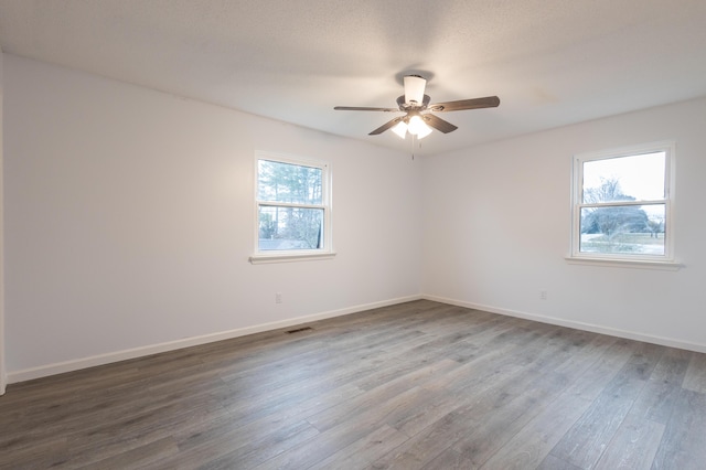 empty room featuring hardwood / wood-style flooring, ceiling fan, and a wealth of natural light