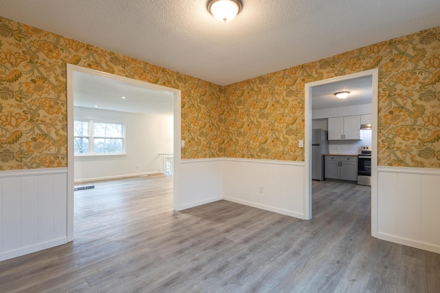 unfurnished room with a textured ceiling and hardwood / wood-style flooring