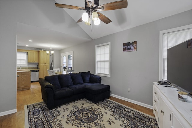 living room featuring ceiling fan with notable chandelier, lofted ceiling, french doors, and light hardwood / wood-style flooring