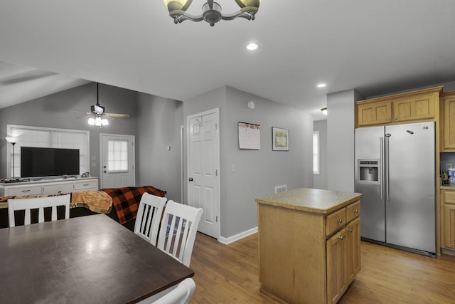 kitchen featuring stainless steel fridge, light hardwood / wood-style floors, vaulted ceiling, a kitchen island, and ceiling fan with notable chandelier