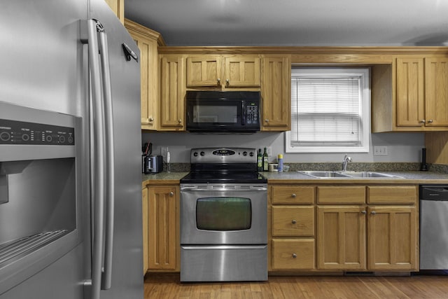 kitchen with appliances with stainless steel finishes, light hardwood / wood-style floors, and sink