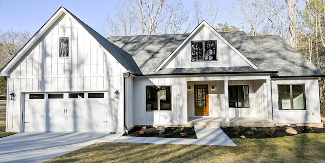 modern inspired farmhouse with a garage, covered porch, and a front lawn