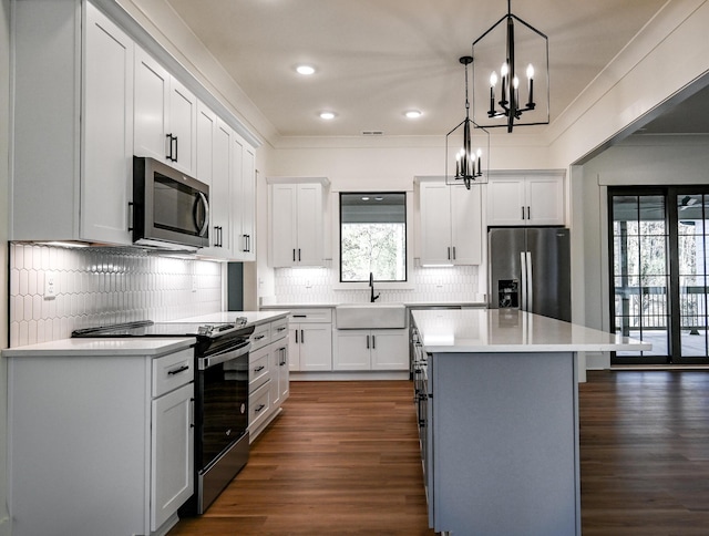 kitchen with white cabinetry, appliances with stainless steel finishes, decorative light fixtures, and a center island