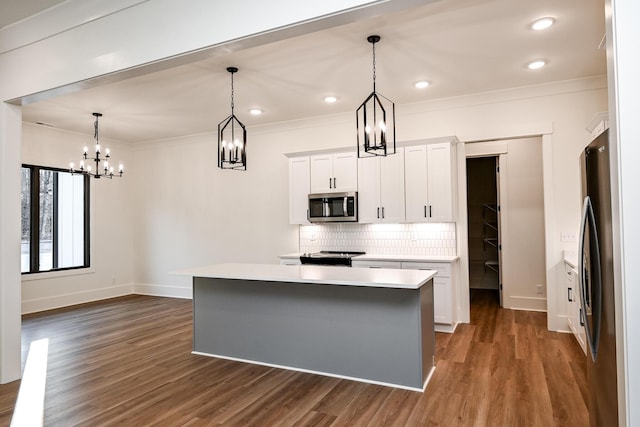 kitchen with decorative light fixtures, stainless steel appliances, white cabinets, and a kitchen island