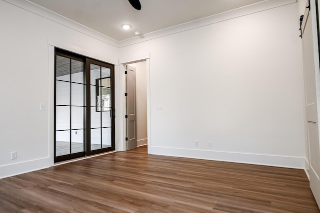 empty room featuring crown molding, dark hardwood / wood-style floors, and a barn door