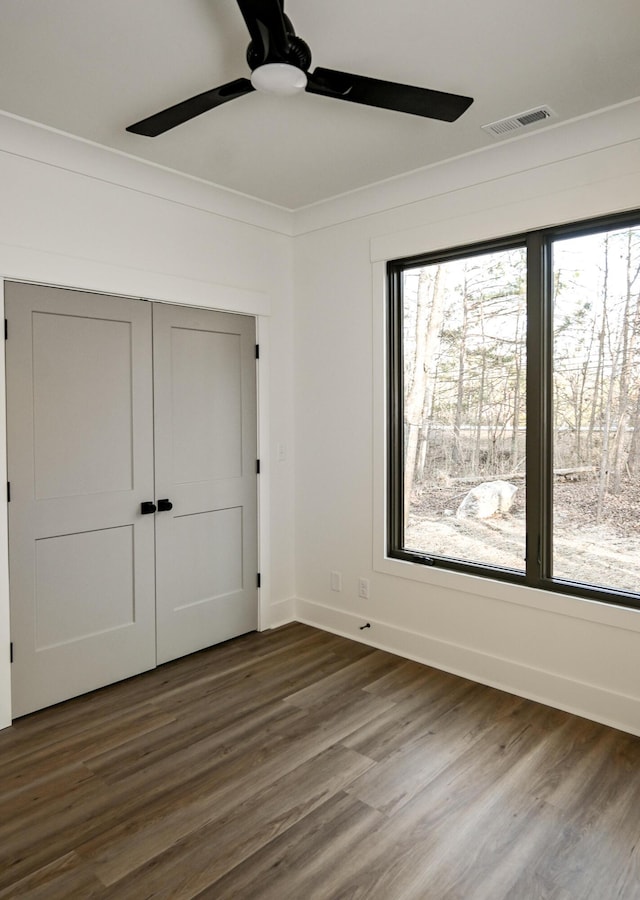 unfurnished bedroom featuring ceiling fan, ornamental molding, dark hardwood / wood-style flooring, and a closet