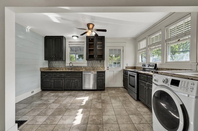 kitchen with dark stone counters, a sink, ceiling fan, washer / dryer, and stainless steel appliances