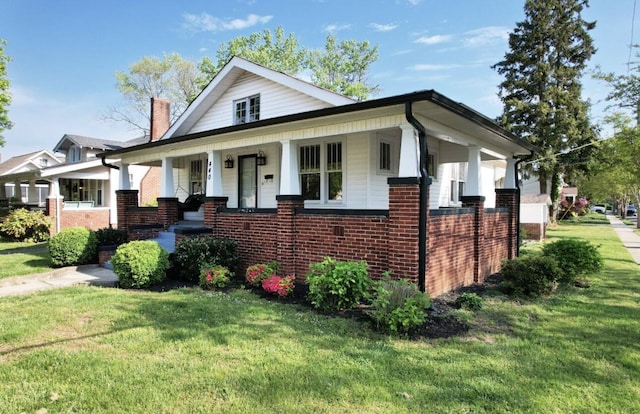 bungalow-style home with brick siding, a porch, and a front yard