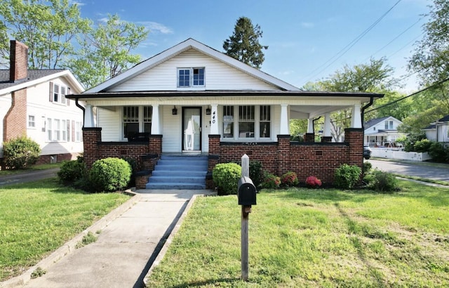 bungalow-style house featuring brick siding, a porch, and a front yard