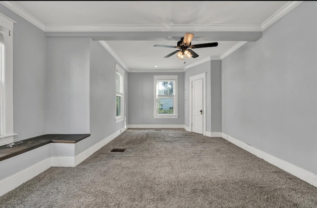 empty room with carpet, visible vents, a ceiling fan, crown molding, and baseboards