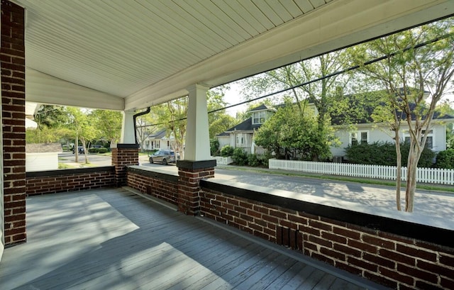 wooden terrace with a residential view, covered porch, and fence
