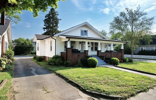view of front facade with brick siding, a front yard, and covered porch