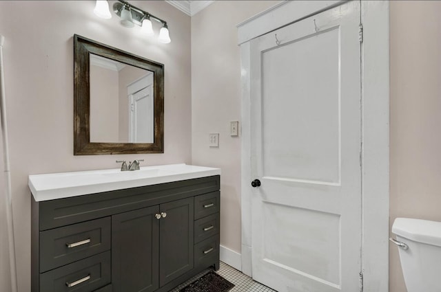 half bathroom with tile patterned floors, vanity, baseboards, toilet, and ornamental molding