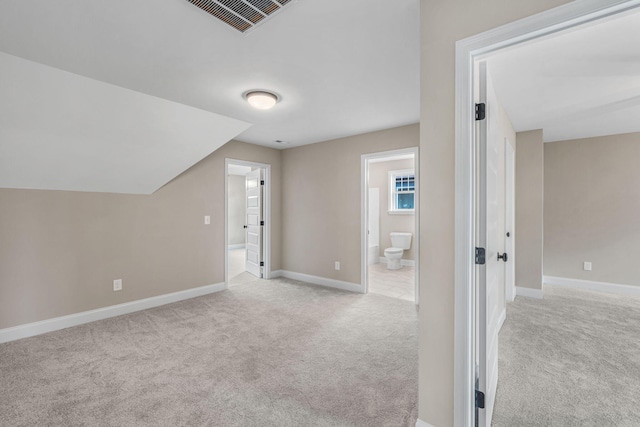 additional living space with light colored carpet and vaulted ceiling