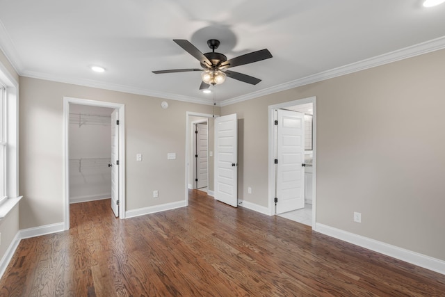 unfurnished bedroom featuring a walk in closet, a closet, ceiling fan, and crown molding