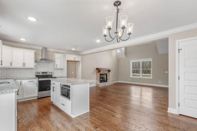 kitchen with wall chimney exhaust hood, built in microwave, electric range, an inviting chandelier, and white cabinets