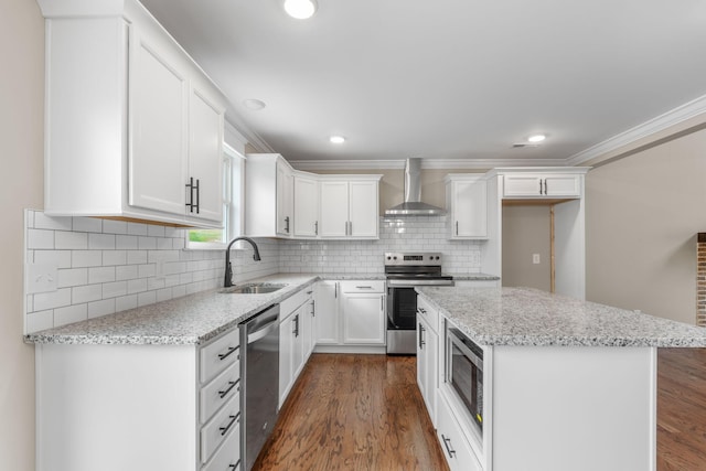 kitchen with sink, wall chimney exhaust hood, appliances with stainless steel finishes, a kitchen island, and white cabinetry