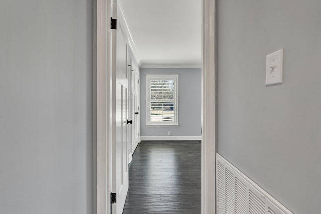corridor with ornamental molding, dark wood-style flooring, visible vents, and baseboards
