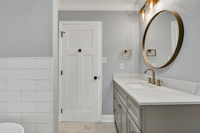 bathroom featuring tile walls, ornamental molding, wood finished floors, and vanity