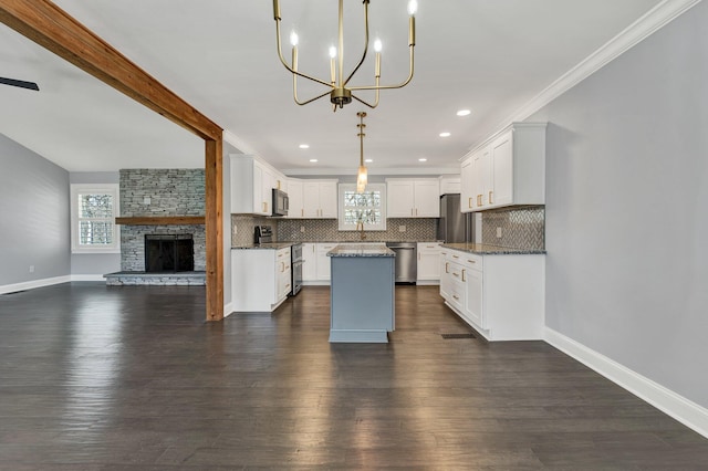 kitchen featuring pendant lighting, appliances with stainless steel finishes, open floor plan, white cabinetry, and a kitchen island