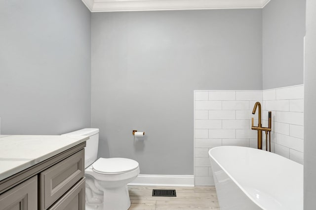 bathroom with visible vents, wood finished floors, vanity, a freestanding tub, and tile walls